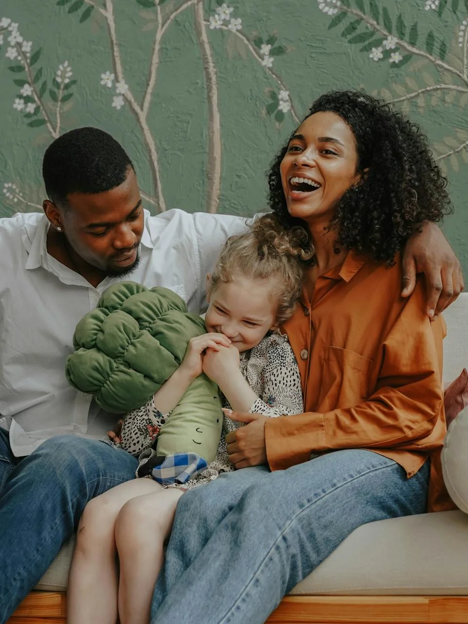 Parents and child laughing together on a cozy living room sofa