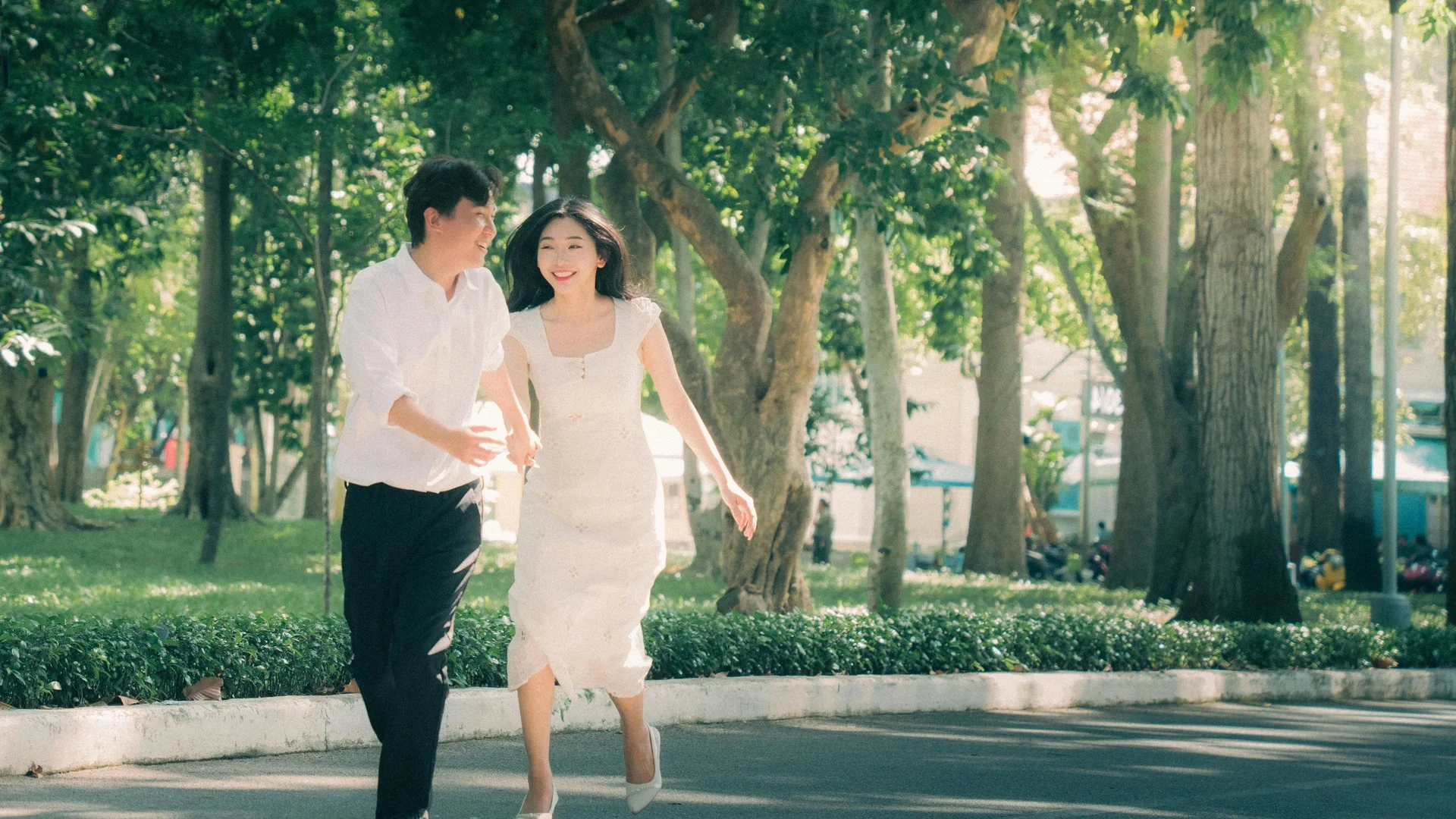 Couple running joyfully together through a sunny park