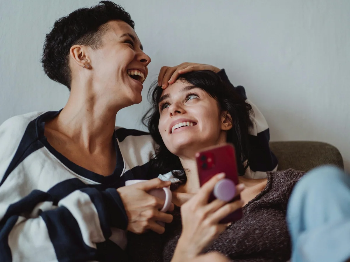 Two women sharing a warm laugh together on the couch