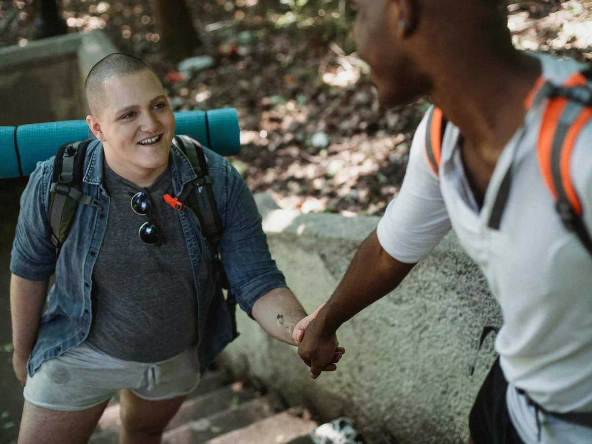 Gay couple holding hands walking up stone stairs in a sunny park