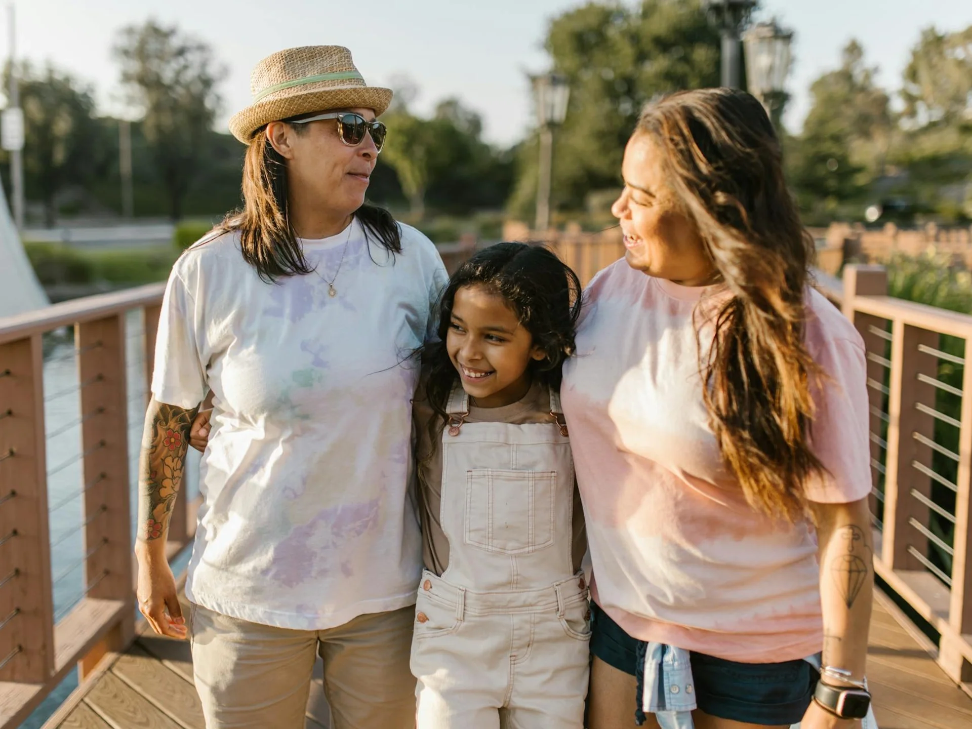 Family enjoying a sunny day walk together on a wooden bridge in a park