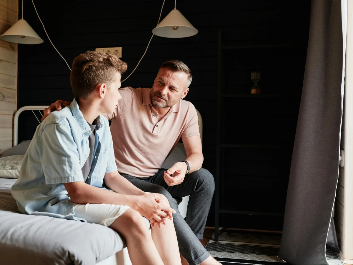 Father and teenage son sharing a supportive conversation at home