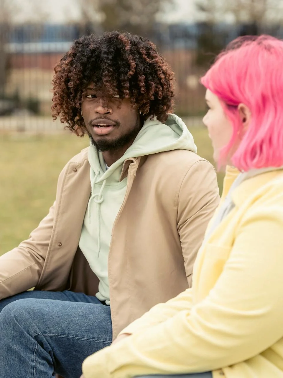 Diverse couple looking at each other while sitting in a park