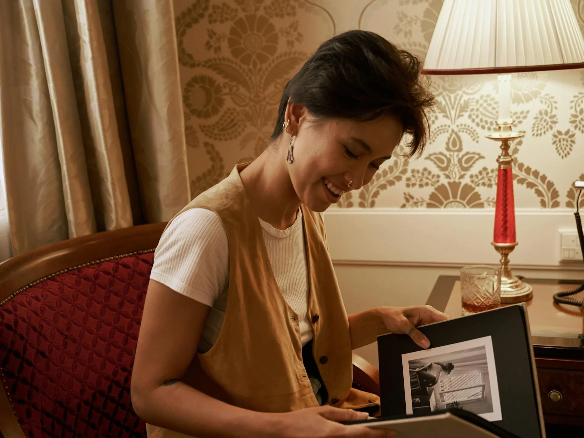Woman smiling as she looks through an old photo album, reconnecting with memories