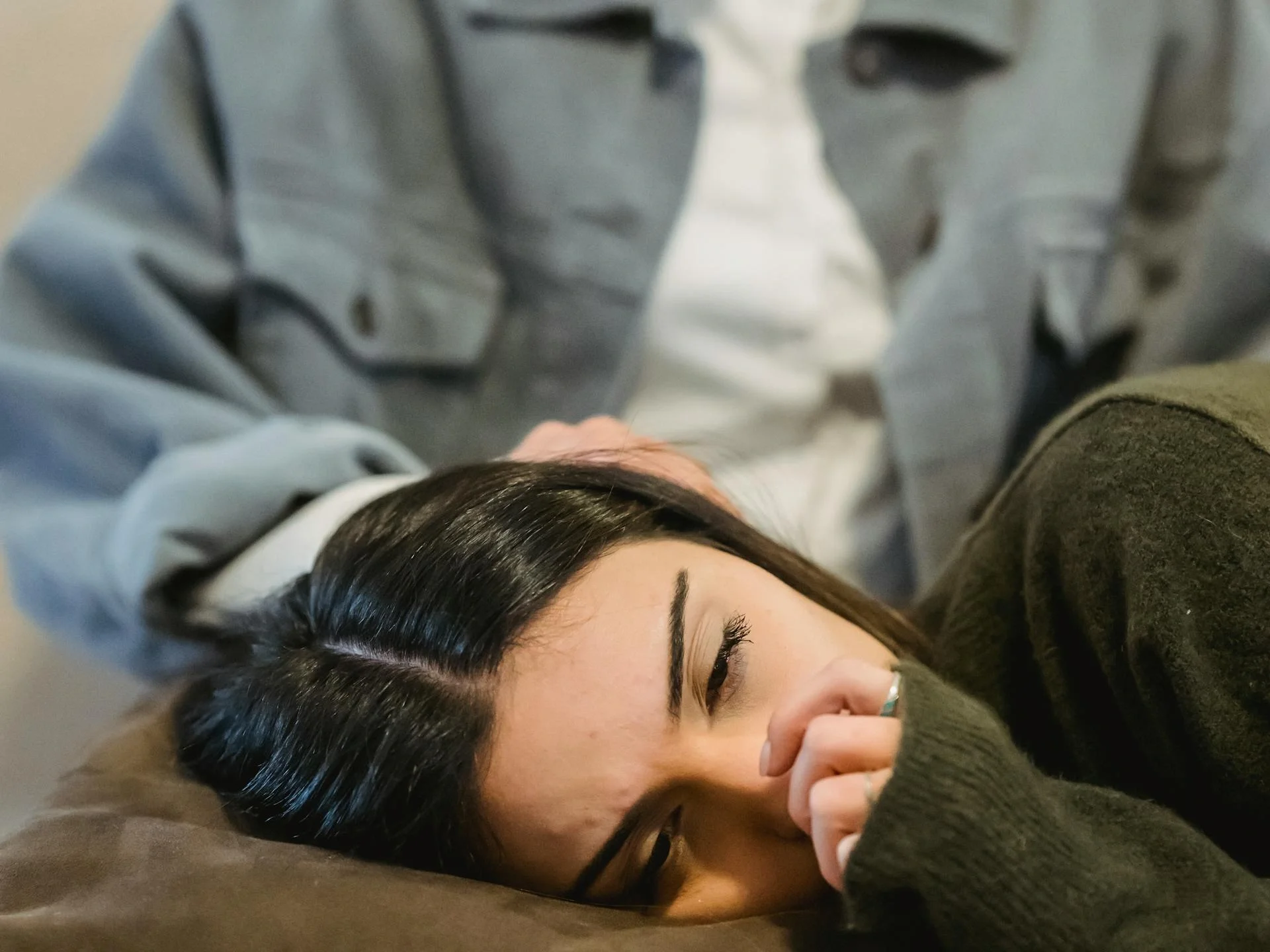 Young woman crying on her friend's lap while receiving comfort on a sofa