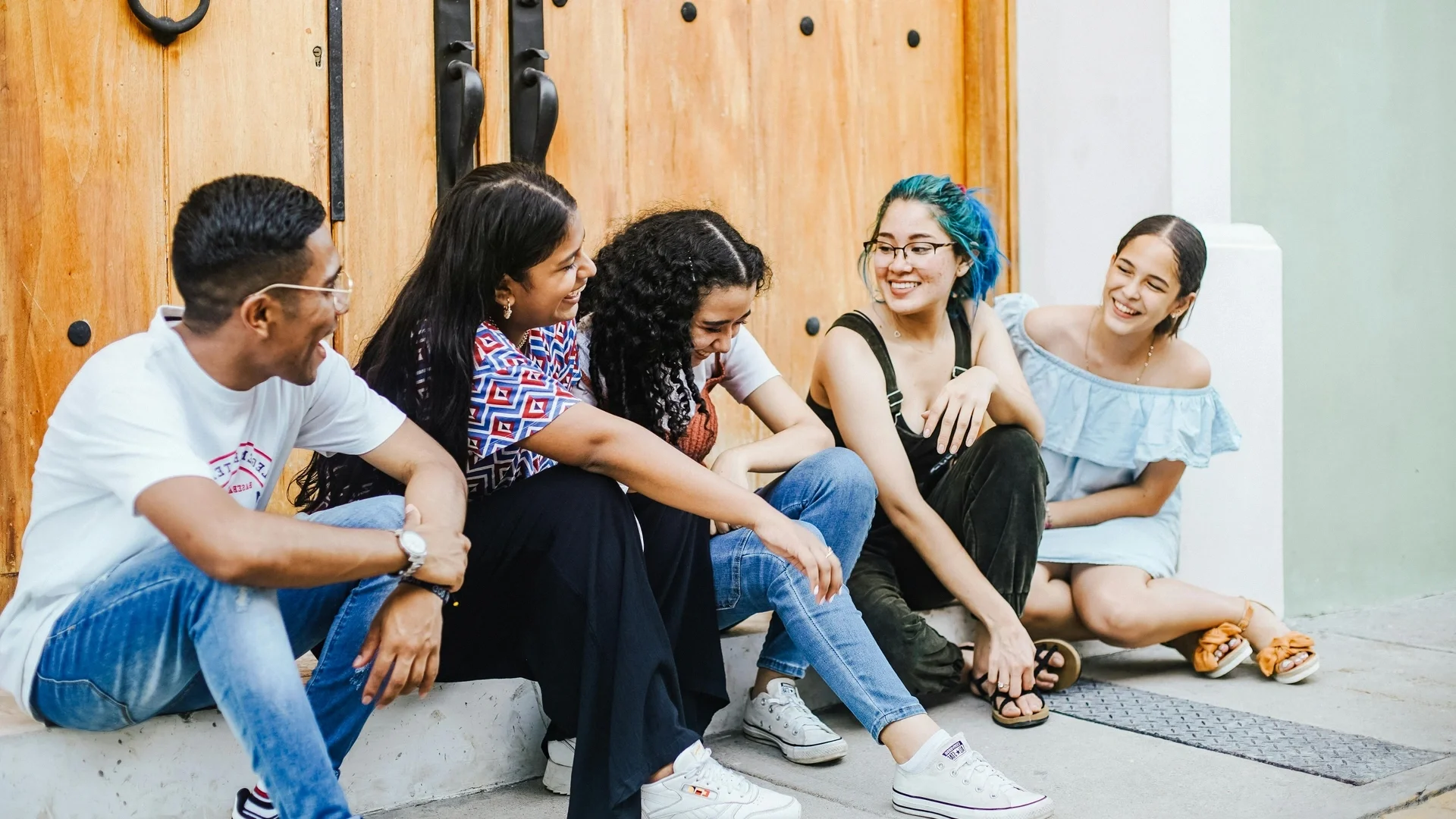 Diverse group of friends laughing together on sunlit steps