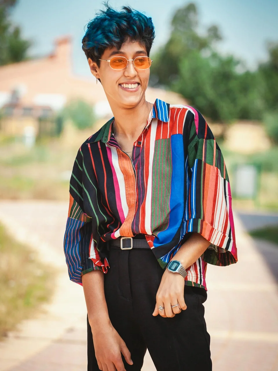 Stylish individual in a colorful shirt and sunglasses, smiling outdoors