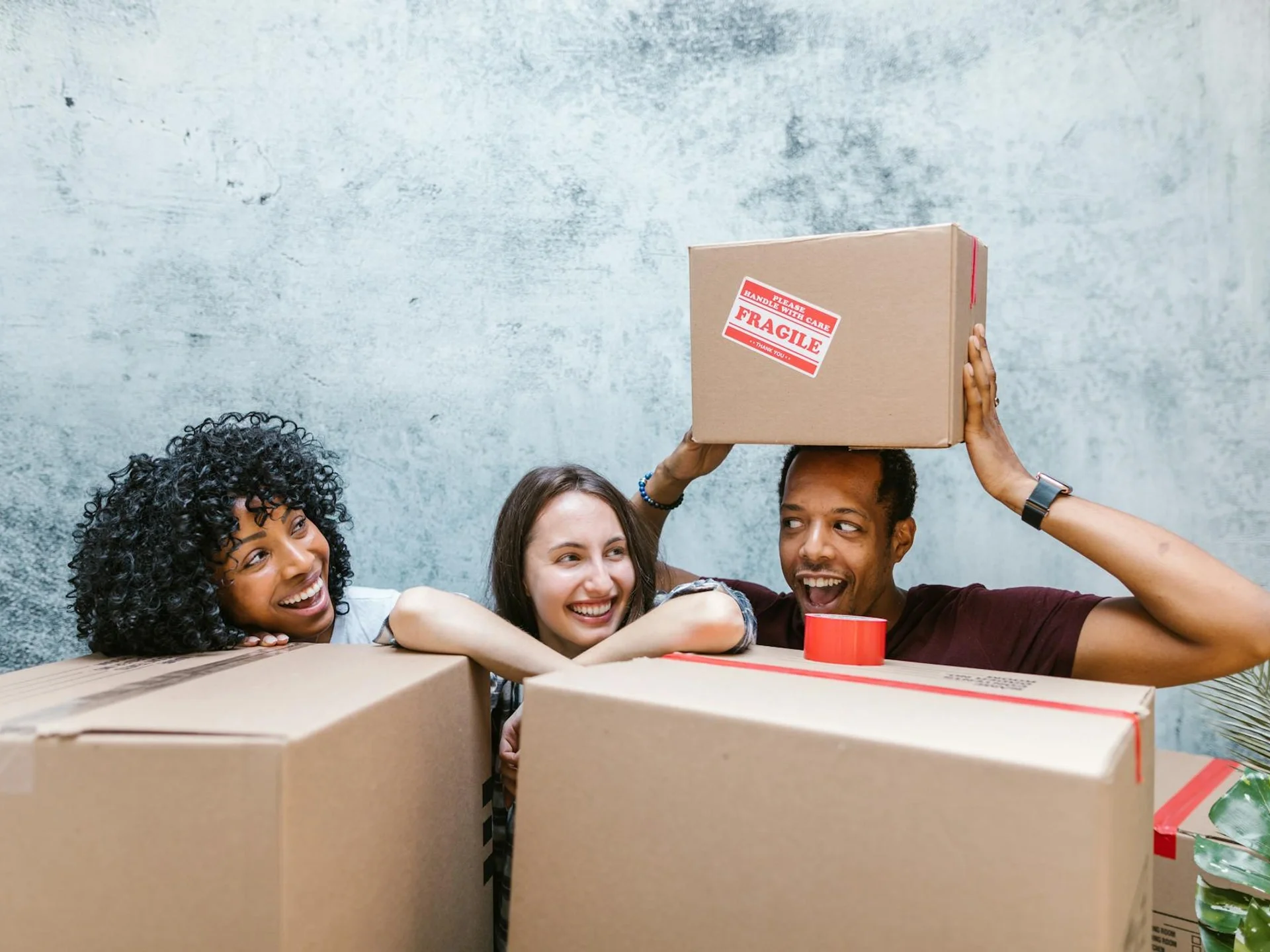Diverse group of friends smiling while packing moving boxes together