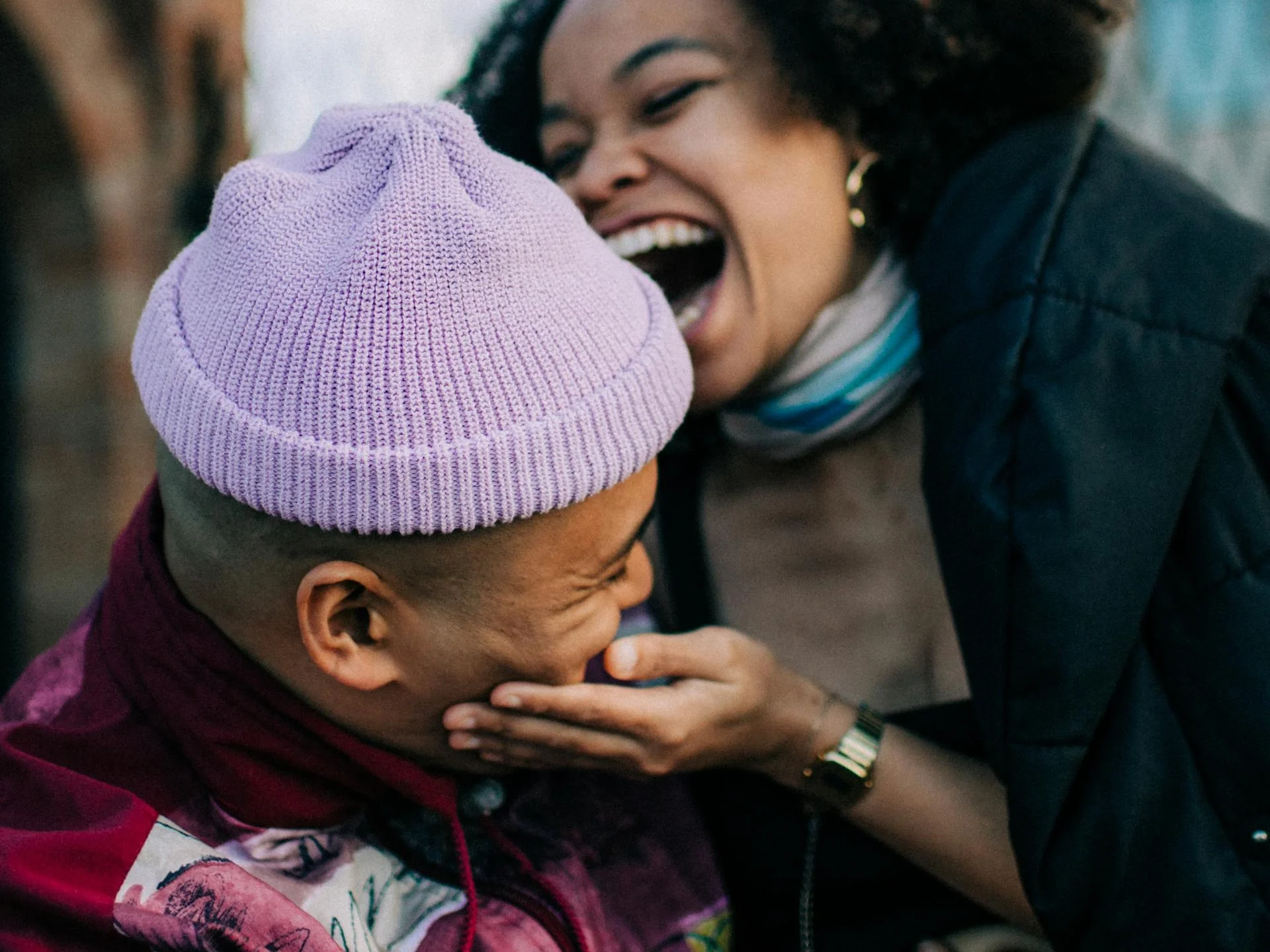 Couple laughing together outdoors, sharing a warm and authentic moment