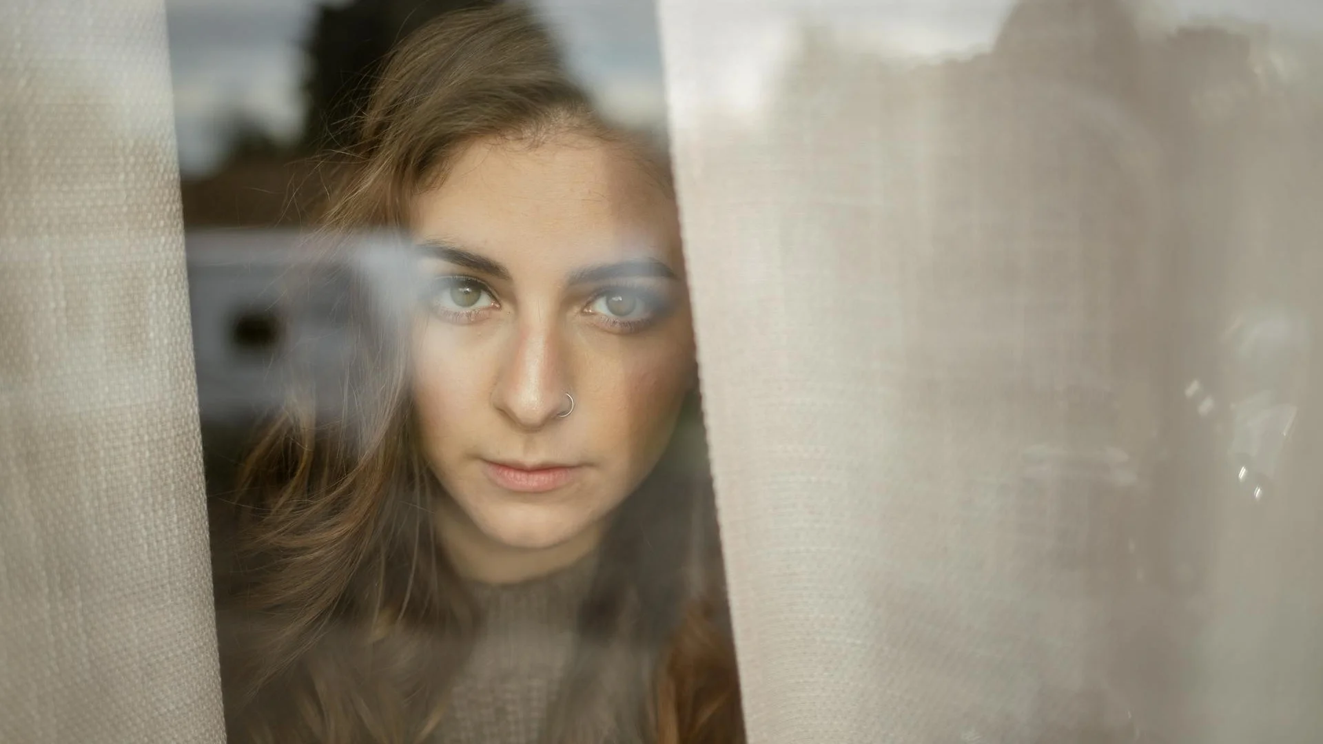 Woman looking thoughtfully through a window in a contemplative mood