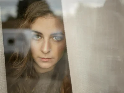 Woman looking thoughtfully through a window in a contemplative mood
