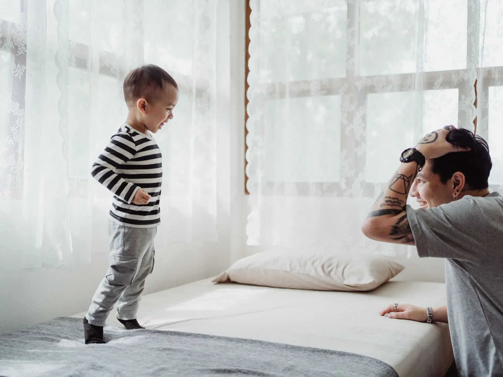 A smiling father playing with his laughing toddler at home