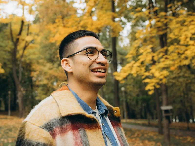 Happy man strolling through an autumn forest park