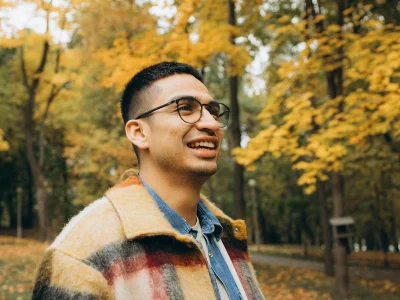 Happy man strolling through an autumn forest park