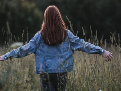 Woman standing in an open field enjoying the freedom of nature