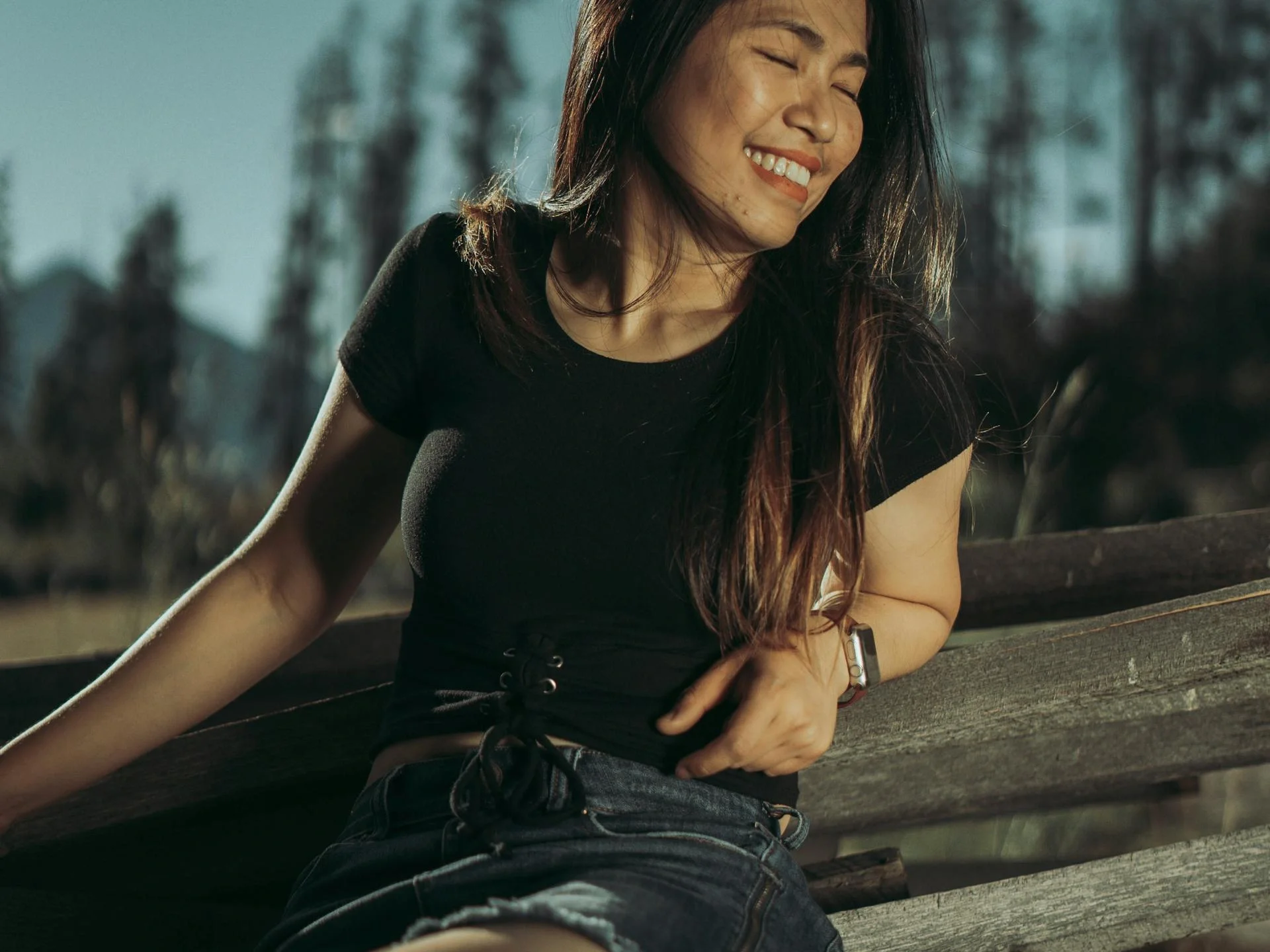 Young woman enjoying a sunny day on a park bench, radiating joy and relaxation