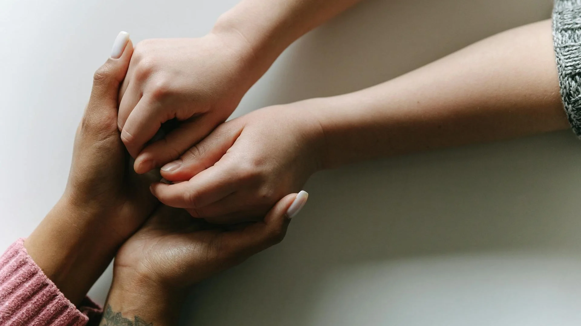 Close-up of diverse hands holding each other in a gesture of care and support