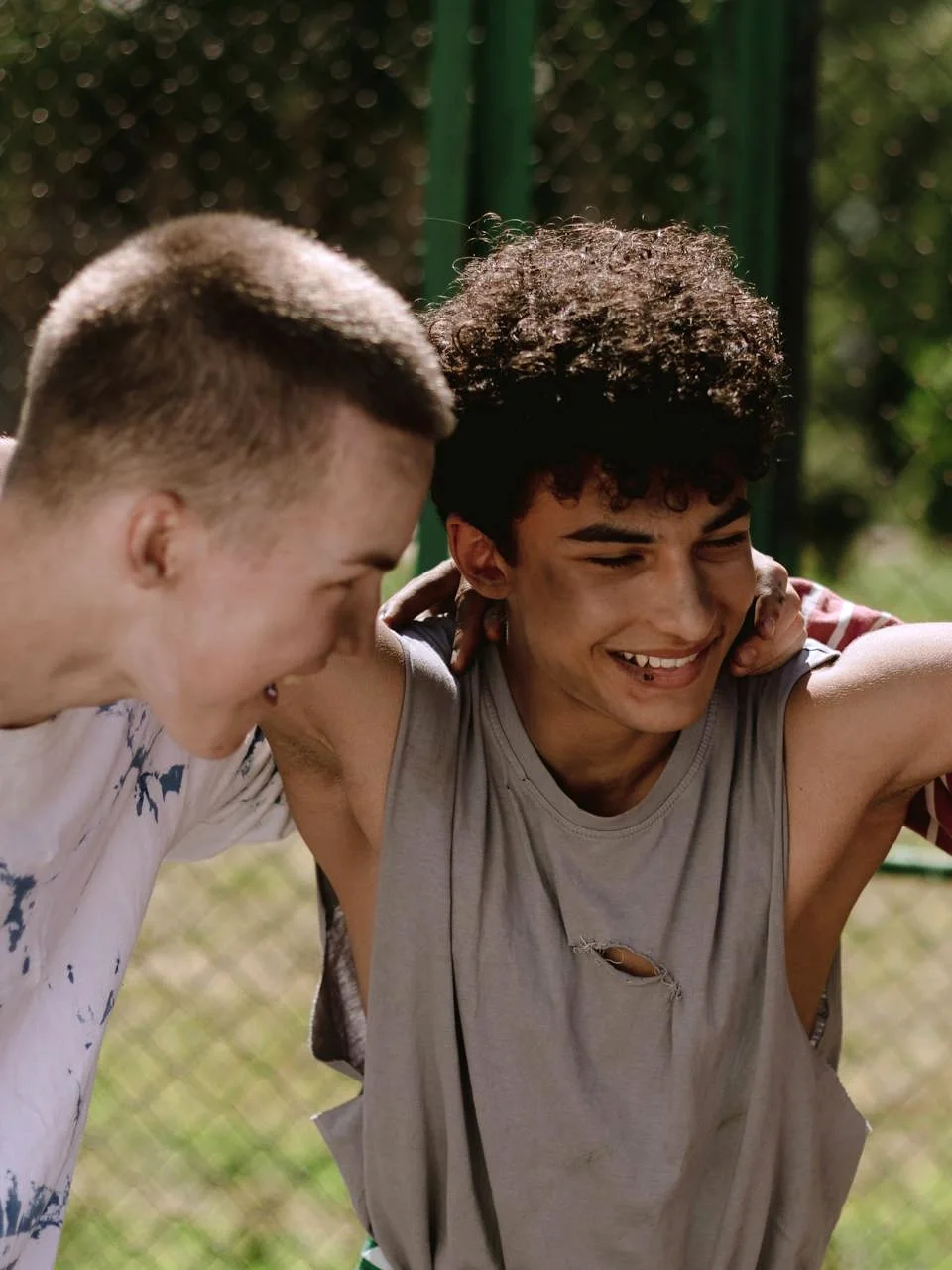 Diverse teenagers laughing and embracing outdoors