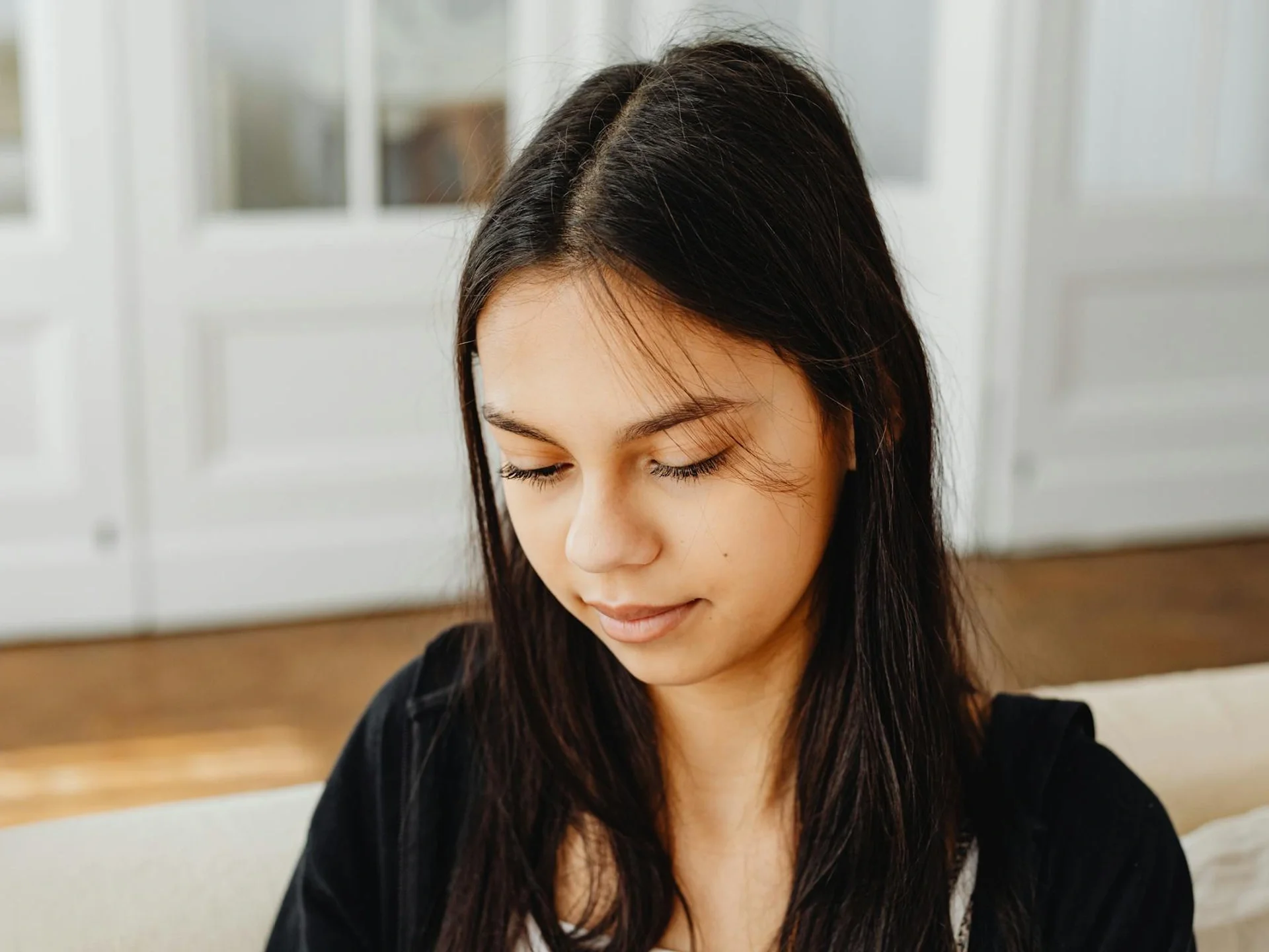 Young woman in a contemplative yet peaceful mood indoors with soft lighting