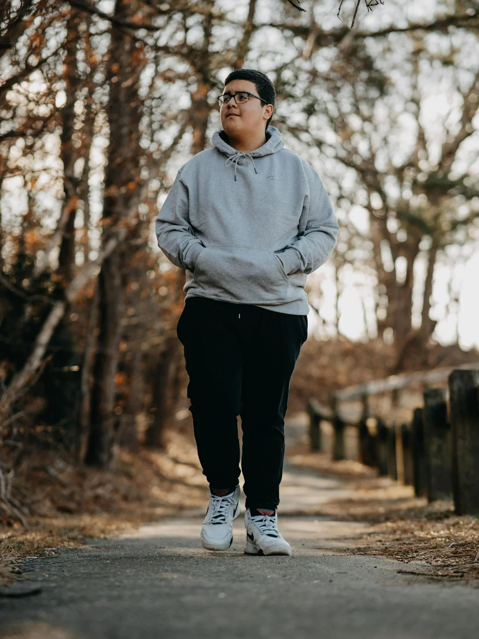 Young man walking on a forest path in a gray hoodie during fall