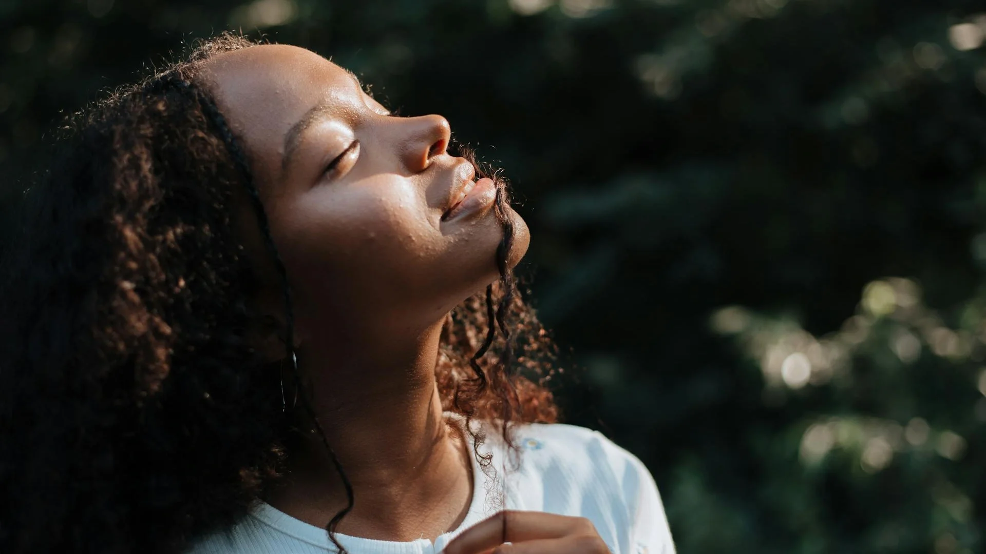 Young woman enjoying warm sunlight filtering through the forest canopy