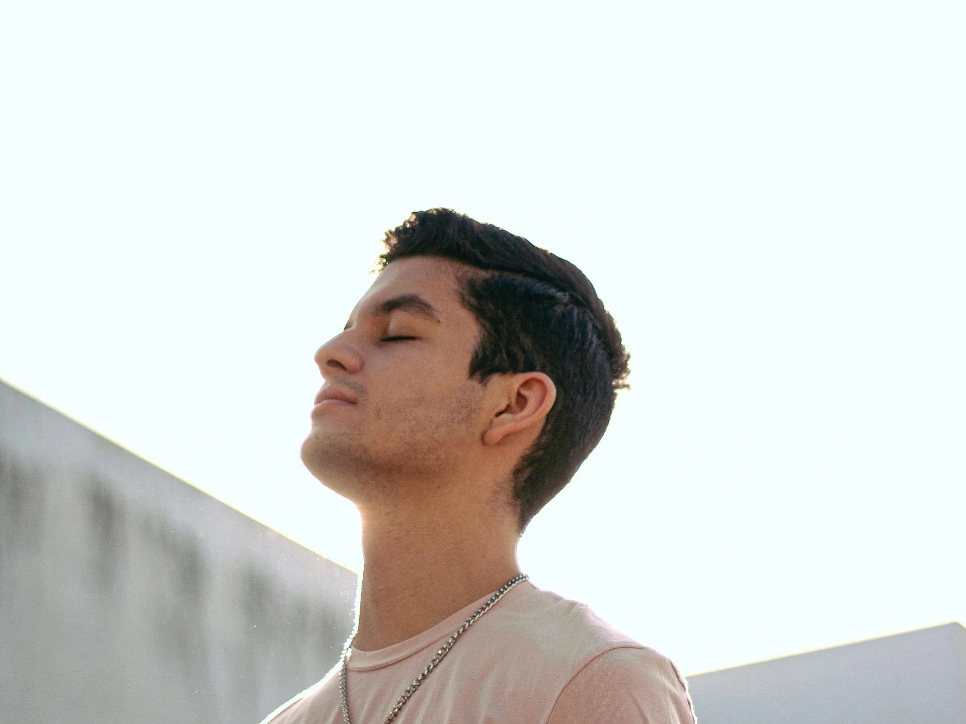 Young man with eyes closed, embracing relaxation in a peaceful outdoor setting